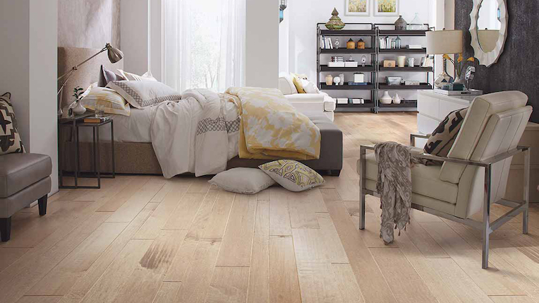 wide planked light toned hardwood flooring in a large, breezy bedroom